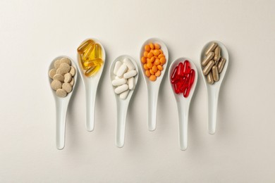 Photo of Spoons with different dietary supplements on white background, flat lay