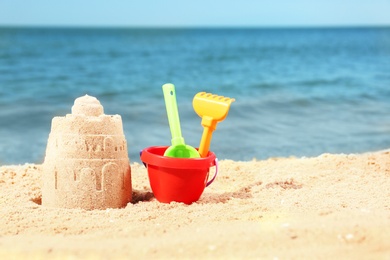 Photo of Beautiful view of beach with sand figure and plastic toys near sea. Space for text