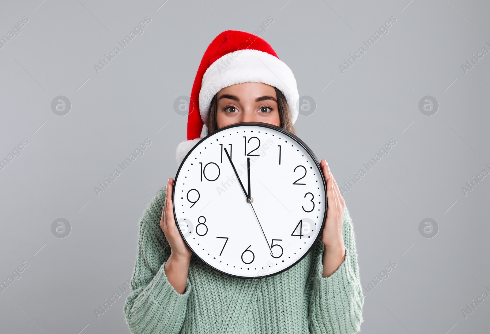 Photo of Woman in Santa hat with clock on grey background. New Year countdown