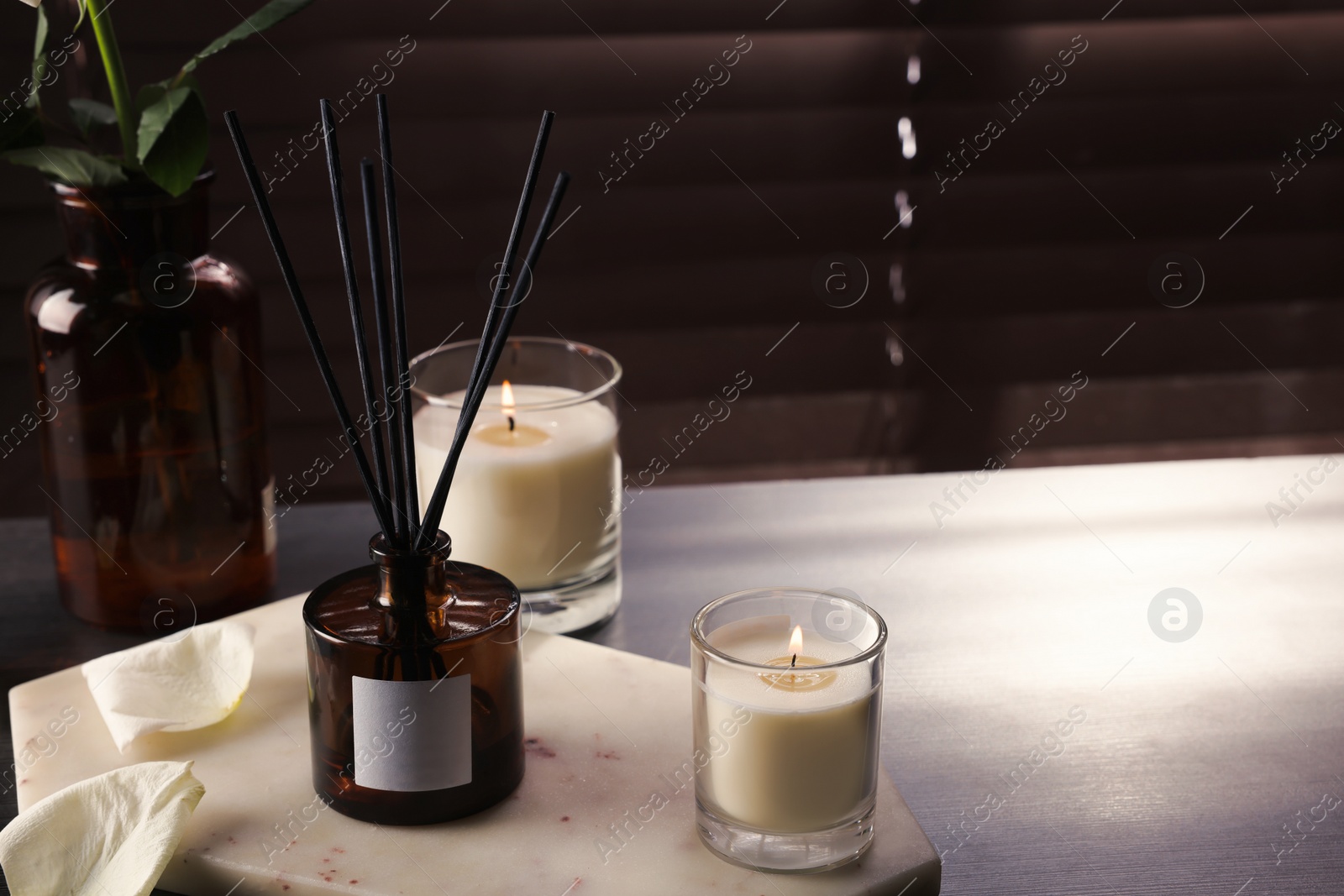 Photo of Aromatic reed air freshener and burning candles on white windowsill, space for text