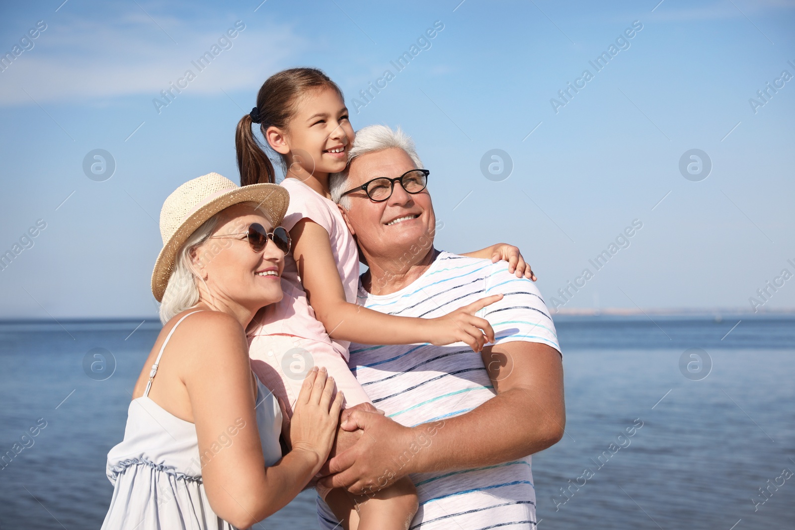 Photo of Little girl with grandparents spending time together  near sea