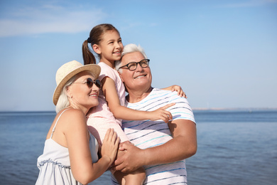 Photo of Little girl with grandparents spending time together  near sea