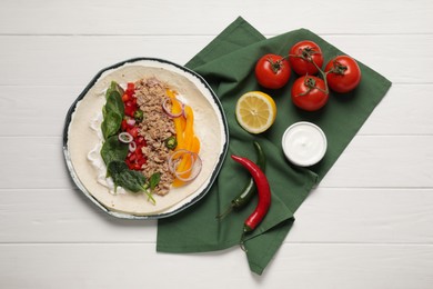 Photo of Delicious tortilla with tuna and vegetables on white wooden table, flat lay. Cooking shawarma
