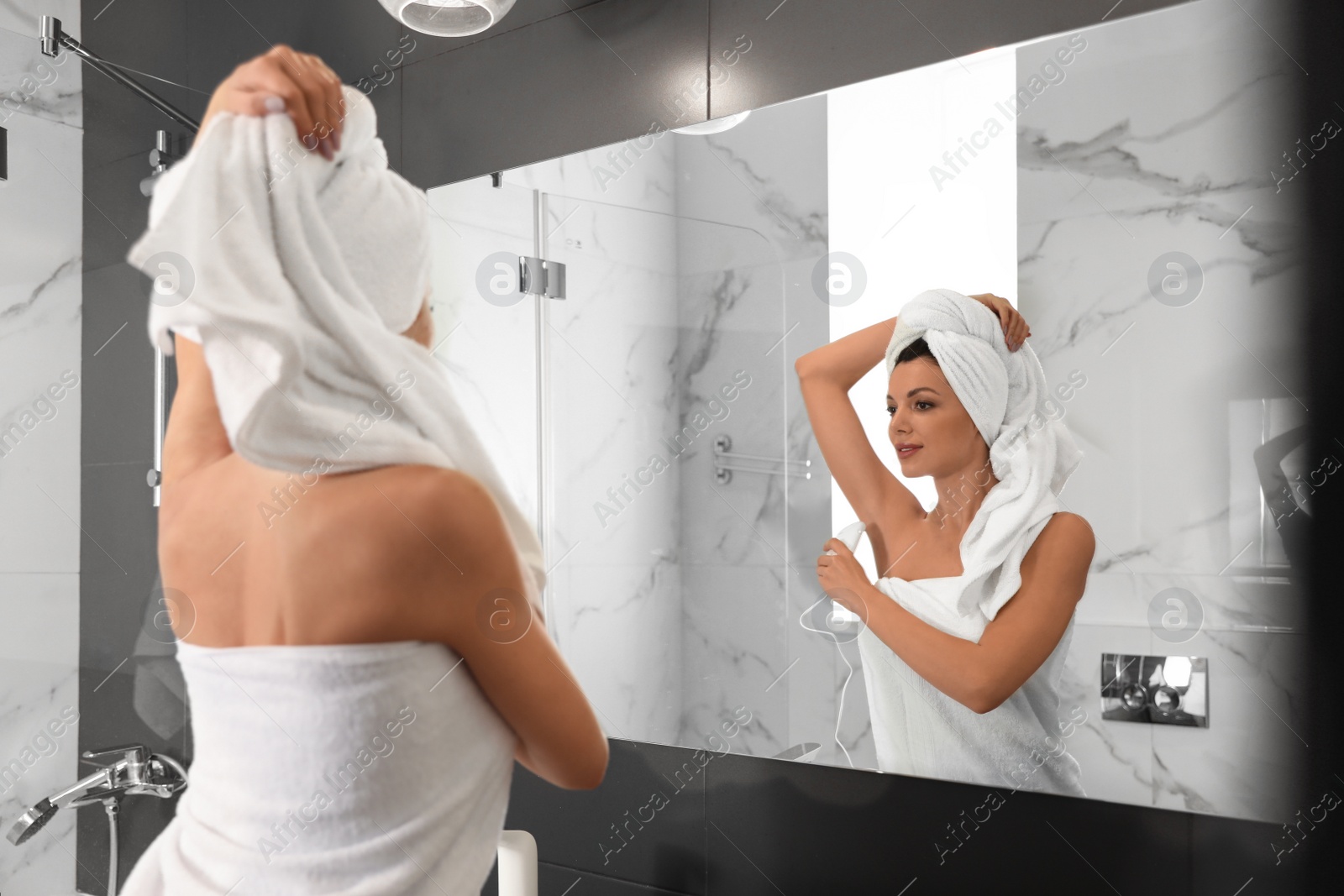Photo of Young woman epilating her armpit in bathroom