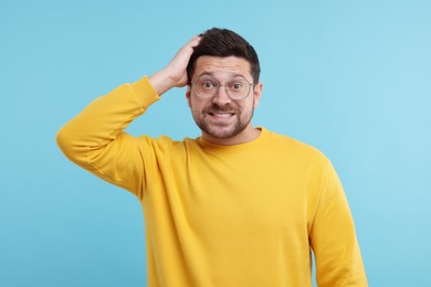 Portrait of embarrassed man on light blue background