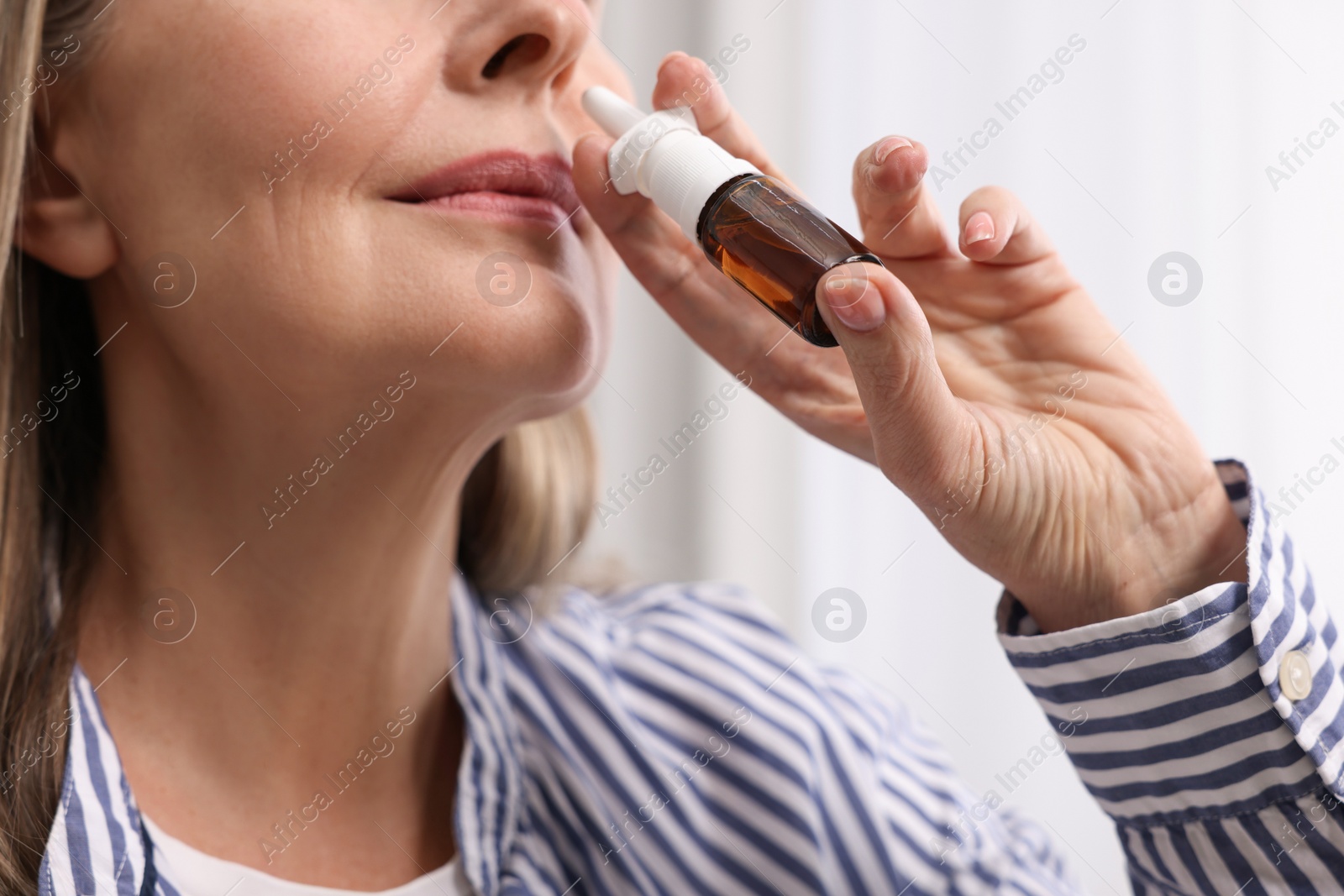 Photo of Medical drops. Woman using nasal spray indoors, closeup