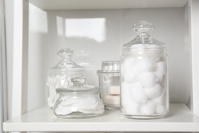 Cotton balls, swabs and pads on white shelf in bathroom