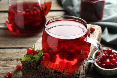 Photo of Delicious cranberry tea and berries on wooden table, closeup