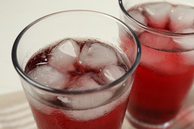 Photo of Refreshing hibiscus tea with ice cubes in glasses on white table, closeup