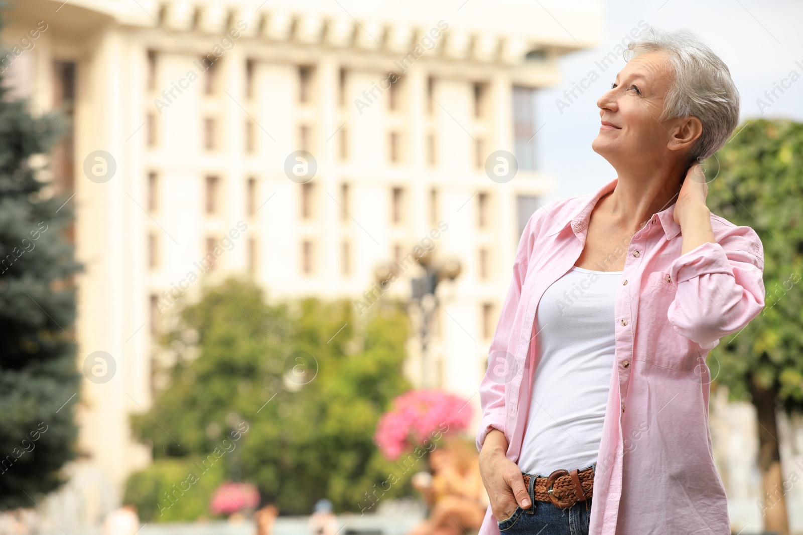 Photo of Happy mature woman on city street, space for text. Smart aging