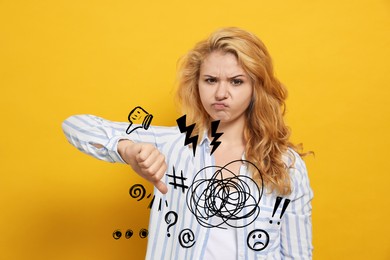 Image of Complaint. Dissatisfied young woman showing thumb down gesture on yellow background, Different illustrations near her hand