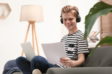 Photo of Online learning. Smiling teenage boy with laptop looking on essay at home