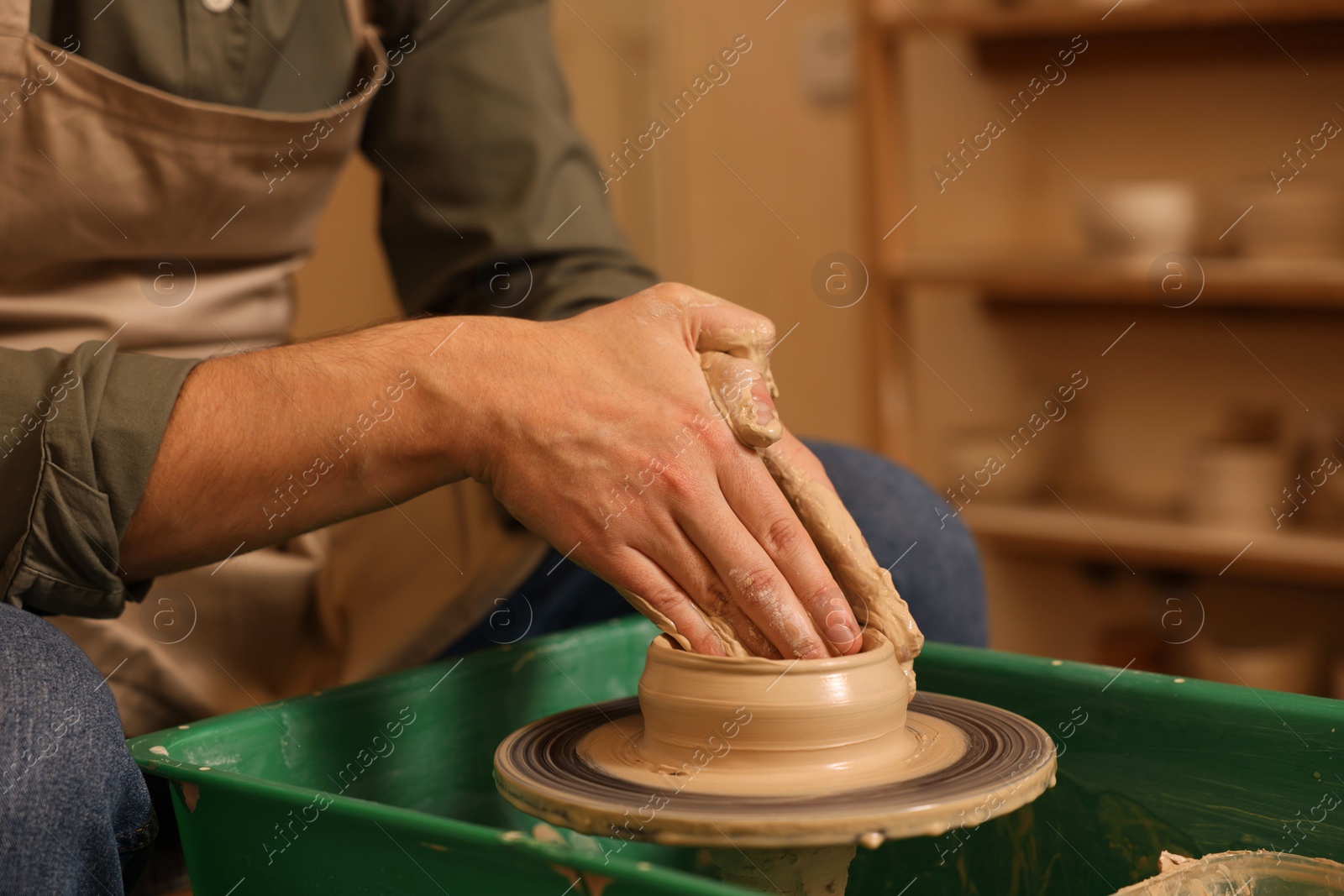 Photo of Clay crafting. Man making bowl on potter's wheel indoors, closeup