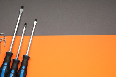 Photo of Set of screwdrivers and screws on color background, flat lay. Space for text