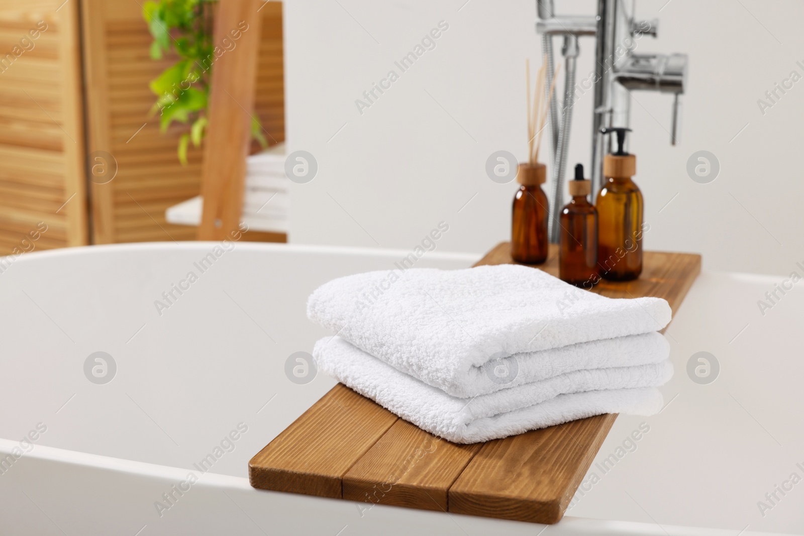 Photo of Stacked soft towels on tub tray in bathroom