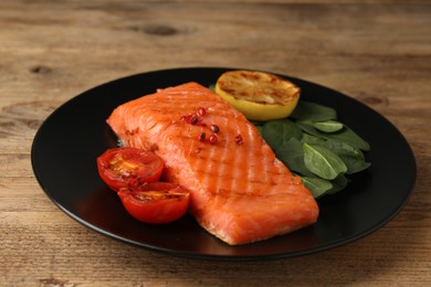 Photo of Tasty grilled salmon with tomatoes, lemon and basil on wooden table, closeup