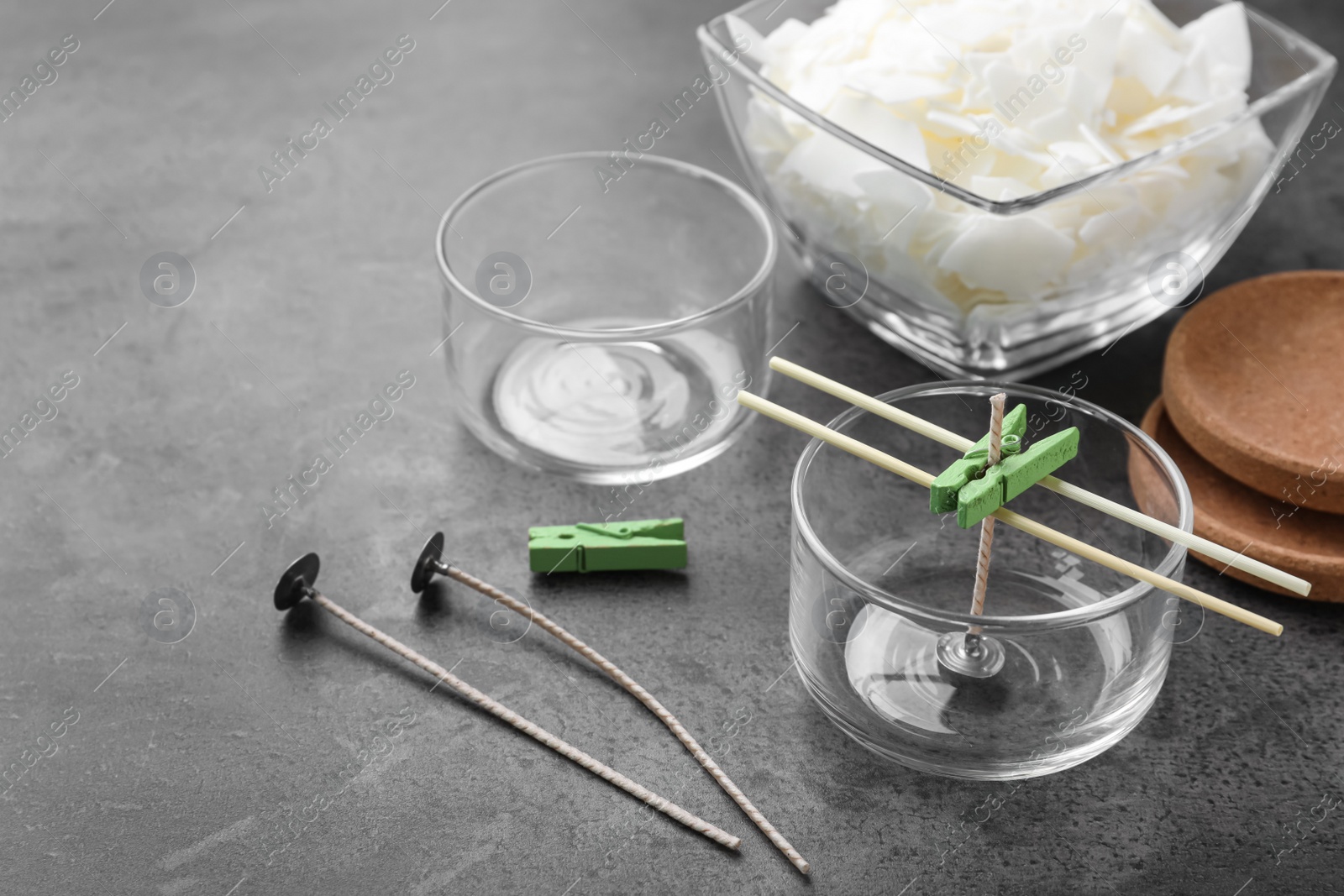 Photo of Glass containers with wicks and wax flakes on grey table. Making homemade candles