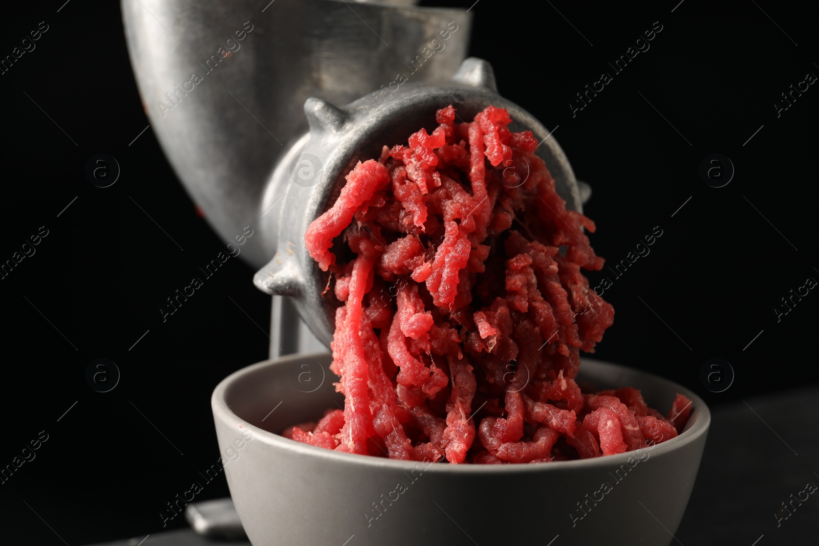 Photo of Metal meat grinder with beef mince on black background, closeup