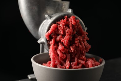 Metal meat grinder with beef mince on black background, closeup