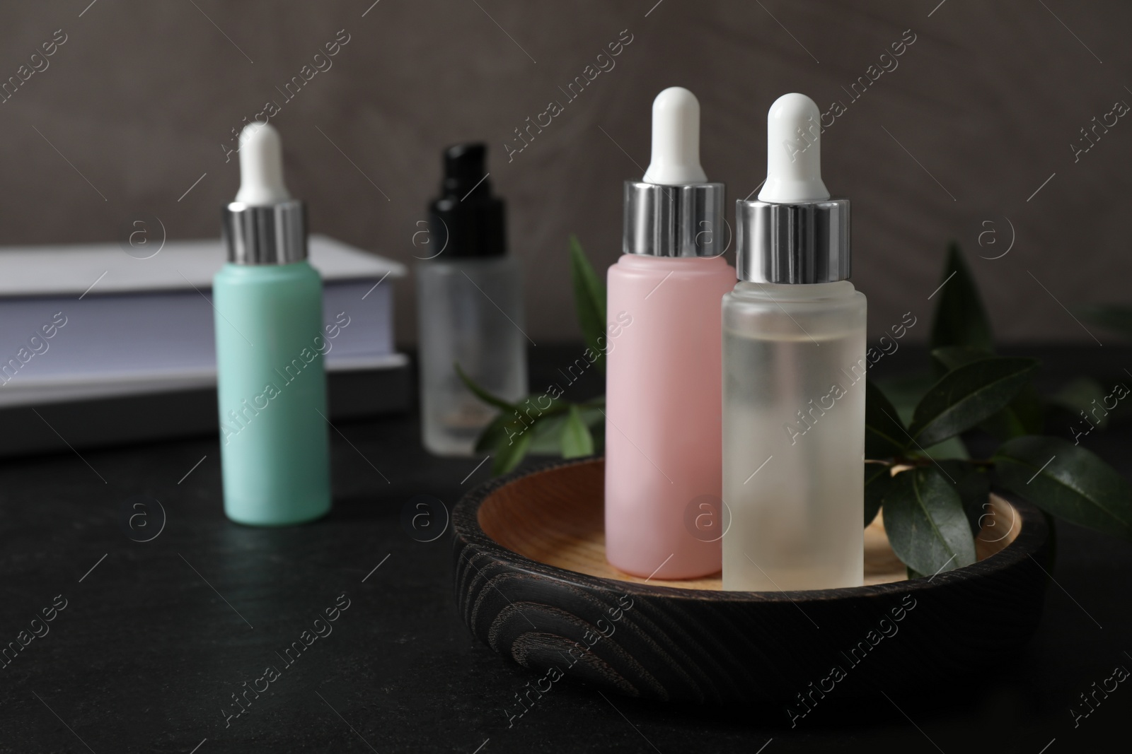 Photo of Bottles of serum on black table, space for text. Cosmetic products