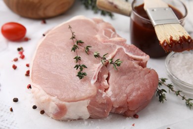 Raw meat, thyme, spices and marinade on white table, closeup