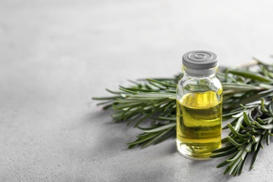 Photo of Bottle with rosemary essential oil on grey background