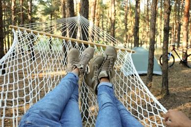 Couple resting in hammock outdoors on summer day, closeup of legs