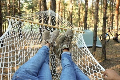 Photo of Couple resting in hammock outdoors on summer day, closeup of legs