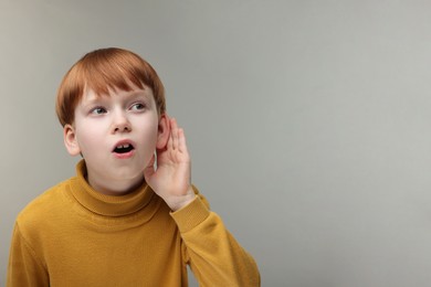 Little boy with hearing problem on grey background, space for text