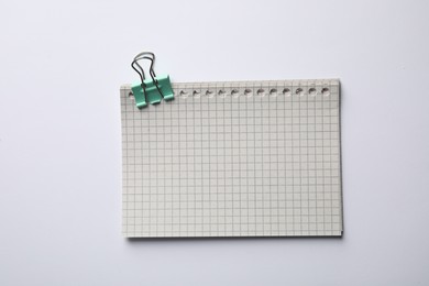 Checkered sheets of paper with binder clip on white background, top view