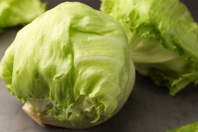 Photo of Fresh green iceberg lettuce heads and leaves on grey table, closeup