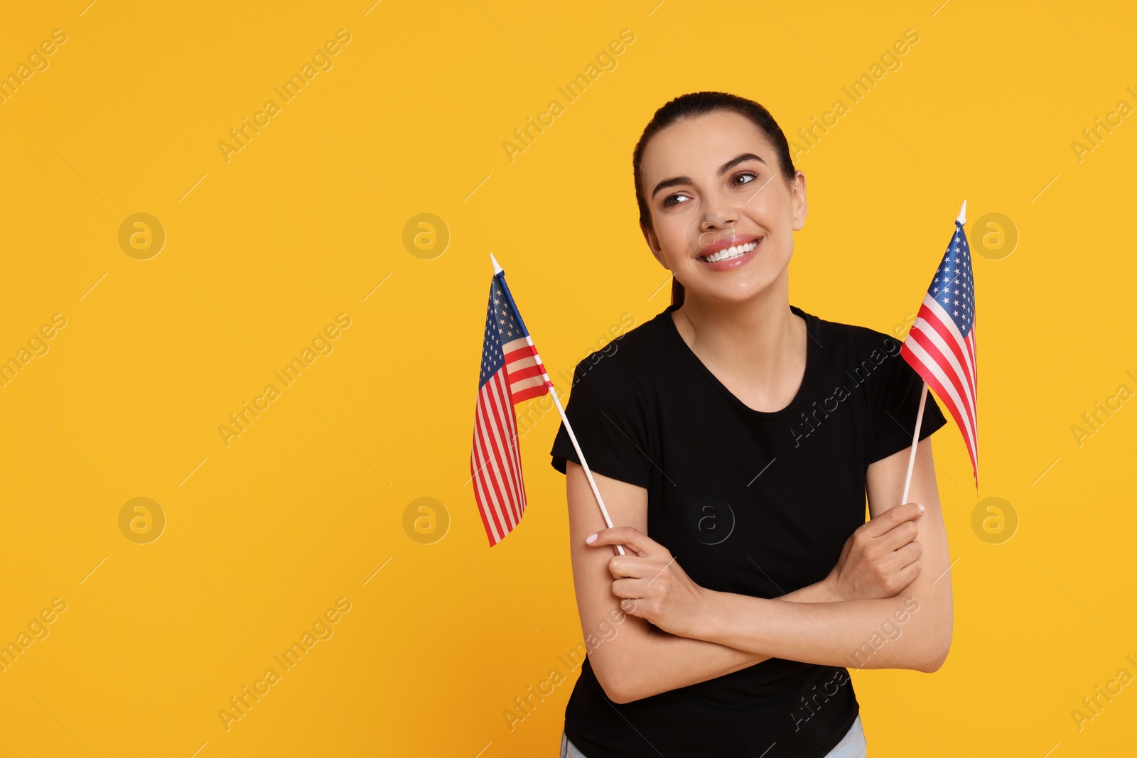 Photo of 4th of July - Independence Day of USA. Happy woman with American flags on yellow background, space for text