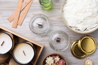 Flat lay composition with homemade candles and ingredients on light wooden background