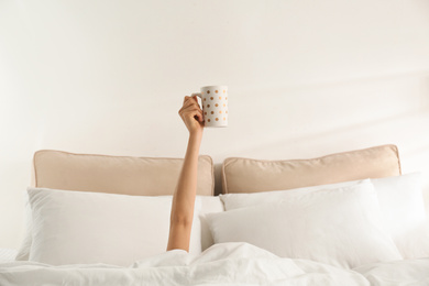 Photo of Woman with cup of coffee in bed, closeup. Lazy morning