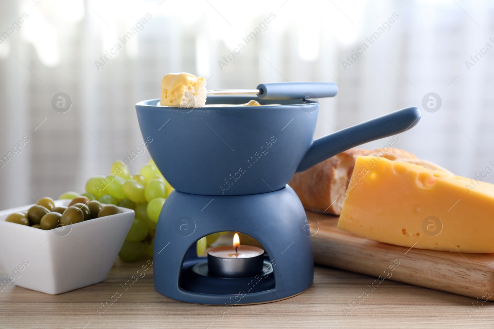 Photo of Pot of tasty cheese fondue and products on table