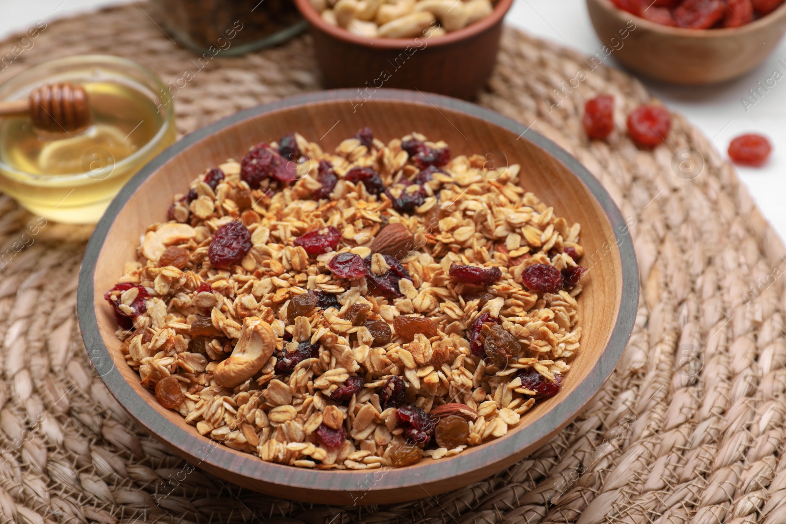 Photo of Tasty granola served with nuts and dry fruits on wicker mat, closeup