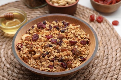 Photo of Tasty granola served with nuts and dry fruits on wicker mat, closeup