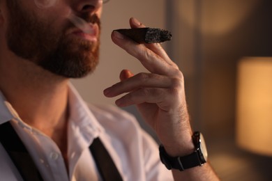 Photo of Man smoking cigar at home, closeup view