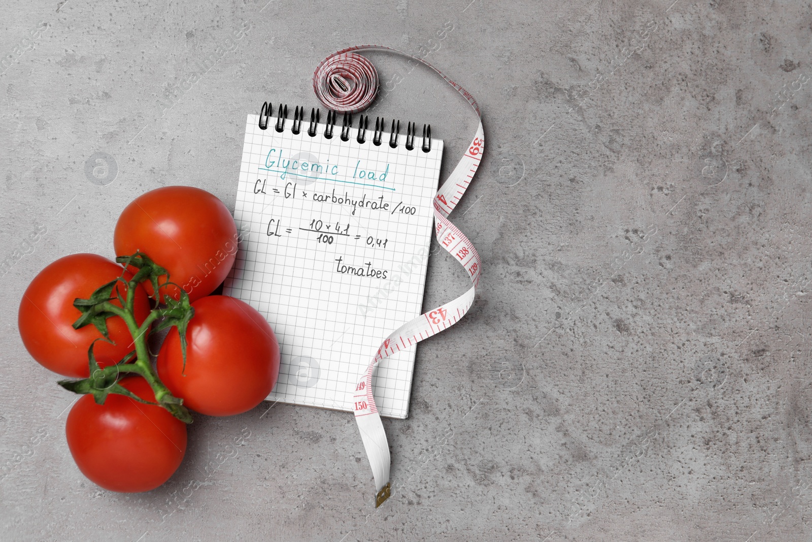 Photo of Notebook with calculated glycemic load for tomatoes, measuring tape and fresh vegetables on grey table, flat lay. Space for text