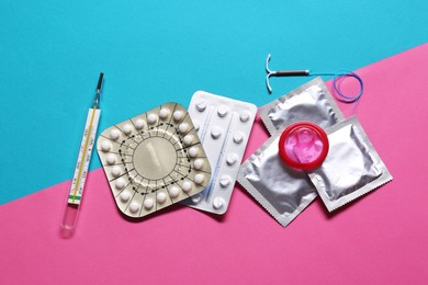 Contraceptive pills, condoms, intrauterine device and thermometer on color background, flat lay. Different birth control methods