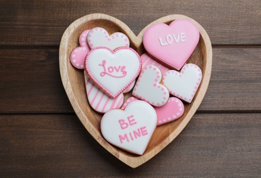 Photo of Delicious heart shaped cookies in bowl on wooden table, top view. Valentine's Day