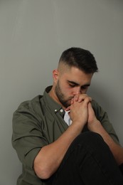 Portrait of sad man near light grey wall