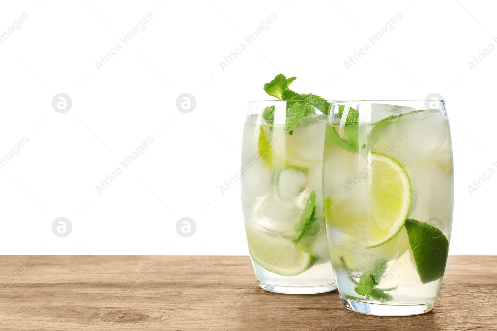 Photo of Glasses of refreshing drink with lime slices and mint on wooden table against white background