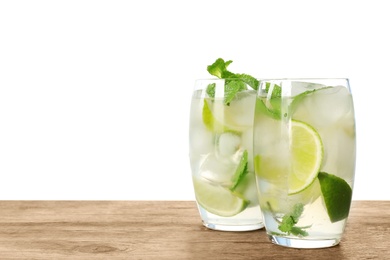 Photo of Glasses of refreshing drink with lime slices and mint on wooden table against white background