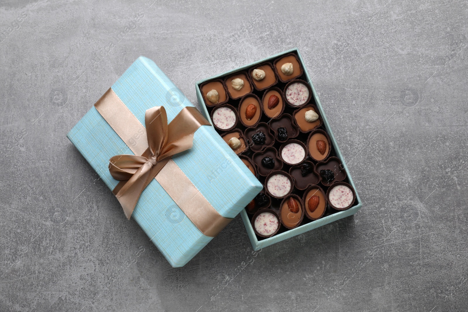 Photo of Open box of delicious chocolate candies on light grey table, top view