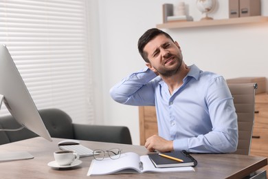 Photo of Man suffering from neck pain in office