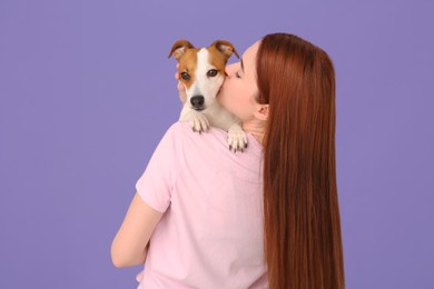 Woman kissing cute Jack Russell Terrier dog on violet background, back view