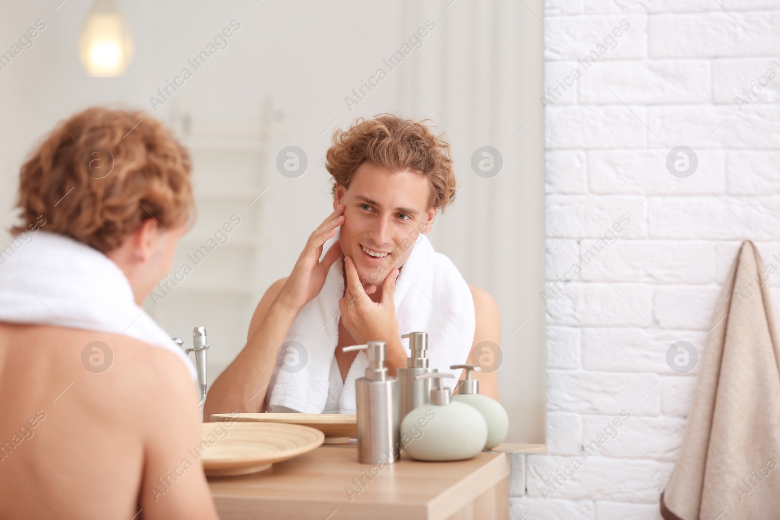 Photo of Young man looking in mirror after shaving at home