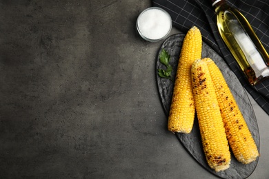 Photo of Fresh grilled corn cobs on grey table, flat lay. Space for text