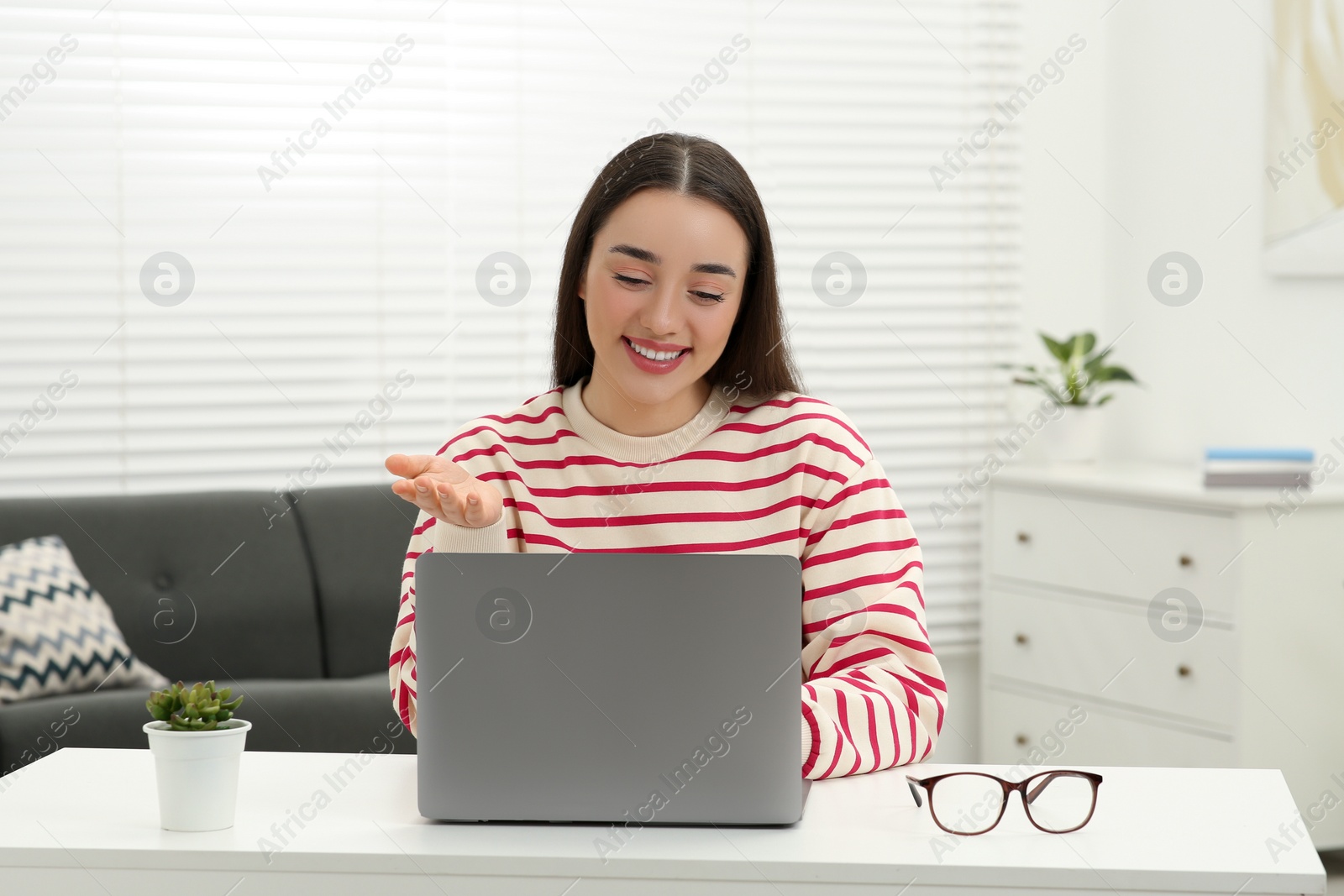 Photo of Woman having video chat via laptop at white table indoors